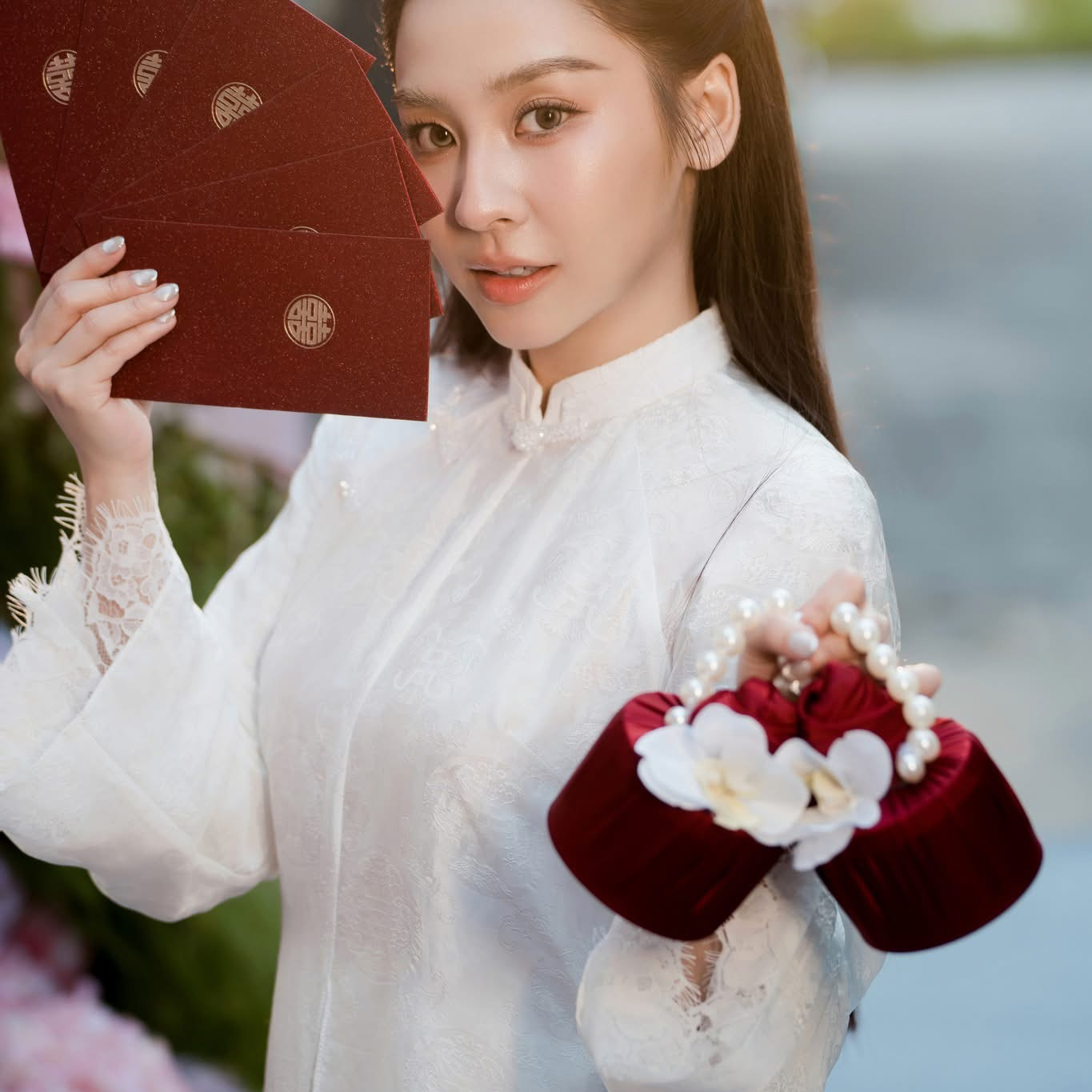 Cô dâu trong áo dài trắng cầm phong bao đỏ