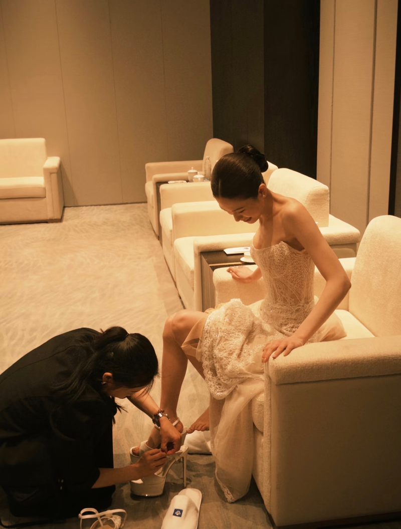 Cô dâu ngồi trên ghế và được hỗ trợ chỉnh giày