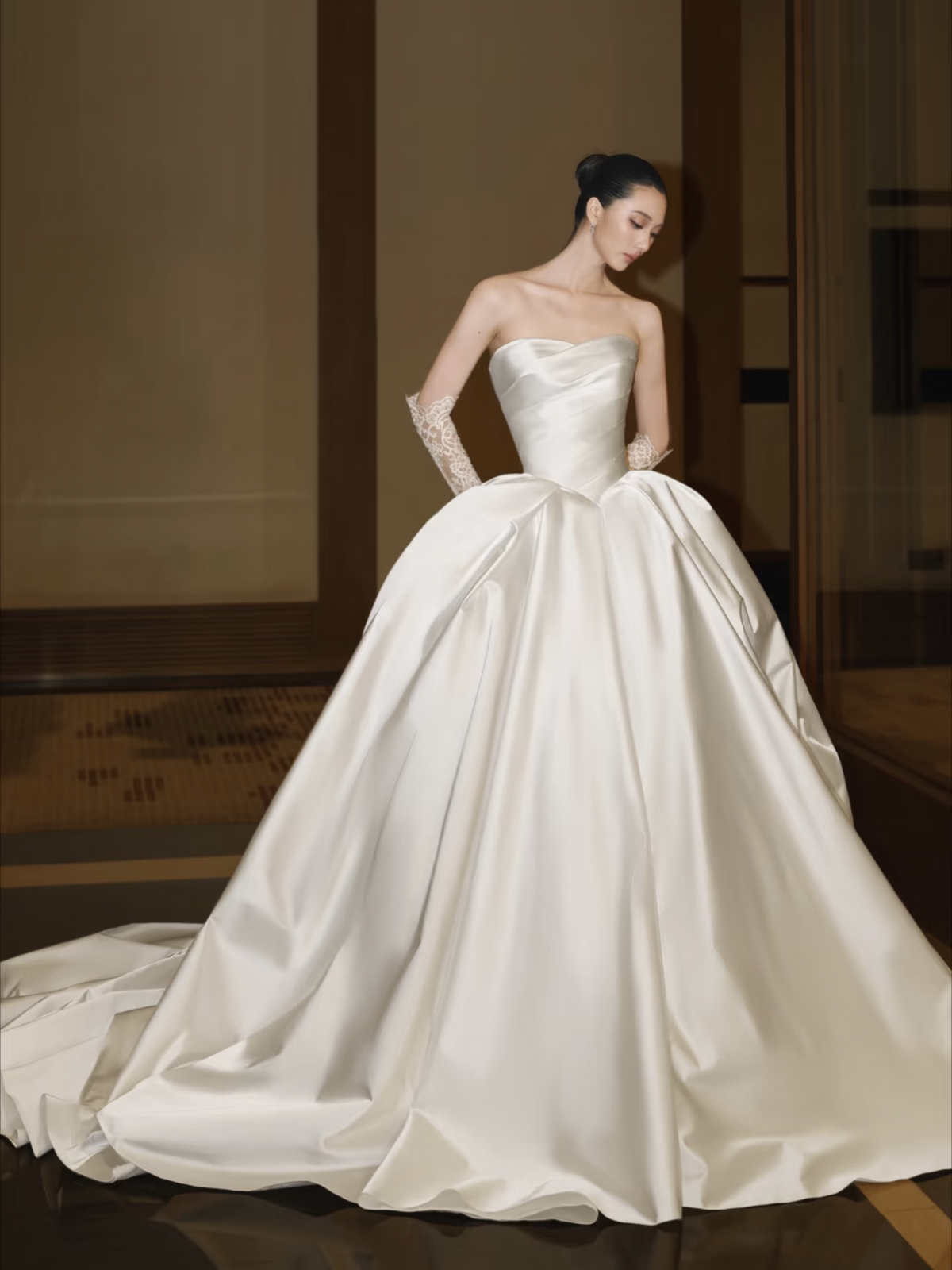 Cô dâu nhìn xuống váy satin xòe tại hành lang
